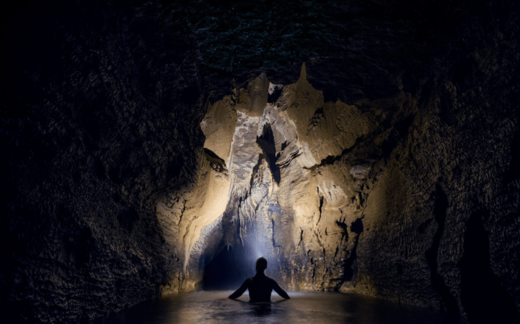 Epic Experience Black Water Rafting in the Waitomo Glowworm Caves 11 Person with headlamp on in the underground Waitomo Caves