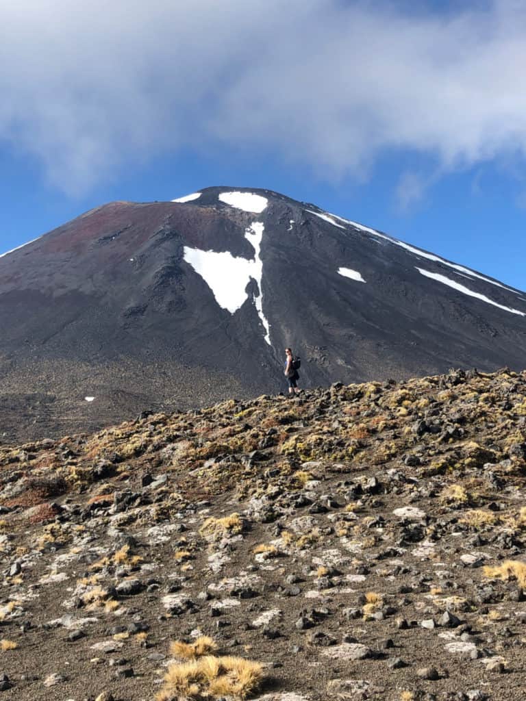 How to Hike the Tongariro Alpine Crossing and Why You'd Want To 5 Nina turning to face the camera in front of Mount Doom halfway up the Tongariro Crossing trail