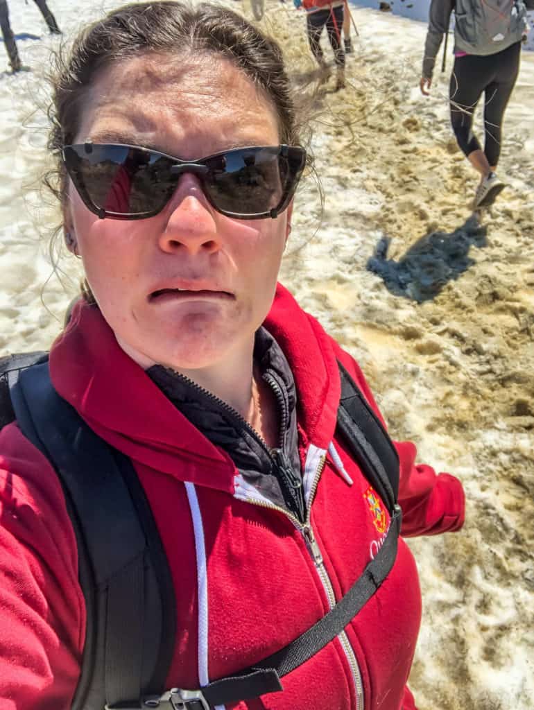 When is winter in New Zealand? (& Should You Visit?) 3 Nina reacting with a grimace to snow on the ground in New Zealand on top of a mountain during winter