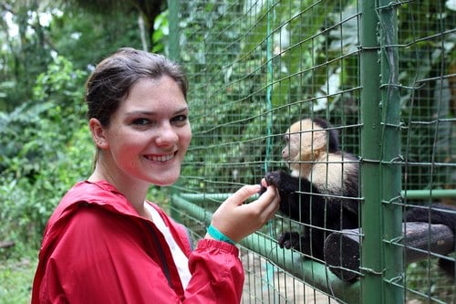 25 Pros and Cons of Living in Costa Rica in 2024 12 16 year old Nina holding hands with a monkey through a cage at the wildlife center she volunteered at.