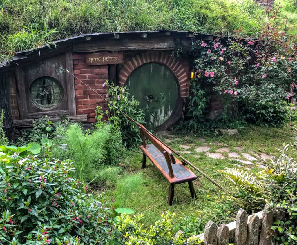 Visiting the Stunning Hobbiton Movie Set in New Zealand 21 Paint peeling on a green hobbit hole door with a sign saying "gone fishing" and a fishing rod out front.