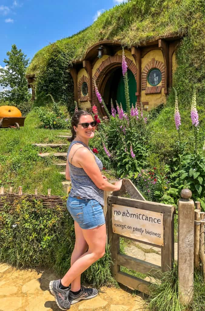 Visiting the Stunning Hobbiton Movie Set in New Zealand 20 Nina posing as she enters Bilbo's gate saying "no admittance". Emerald green hobbit door up the garden path.