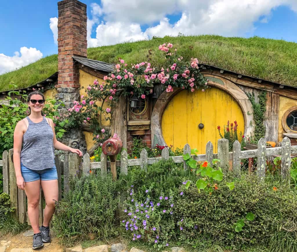 Visiting the Stunning Hobbiton Movie Set in New Zealand 8 Nina posing outside of Samwise's yellow hobbit hole from the Hobbit movie at Hobbiton in New Zealand