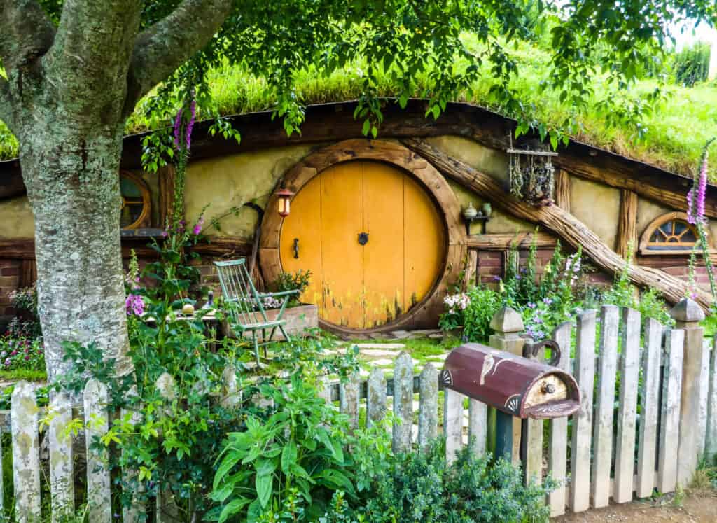 Visiting the Stunning Hobbiton Movie Set in New Zealand 7 Orange circular Hobbiton village dwelling with a mailbox and front garden.
