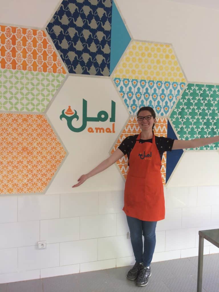 Baking with Moroccan Women at Amal Non-Profit in Marrakech 3 A non-profit worker in an apron standing in front of a colorful wall.