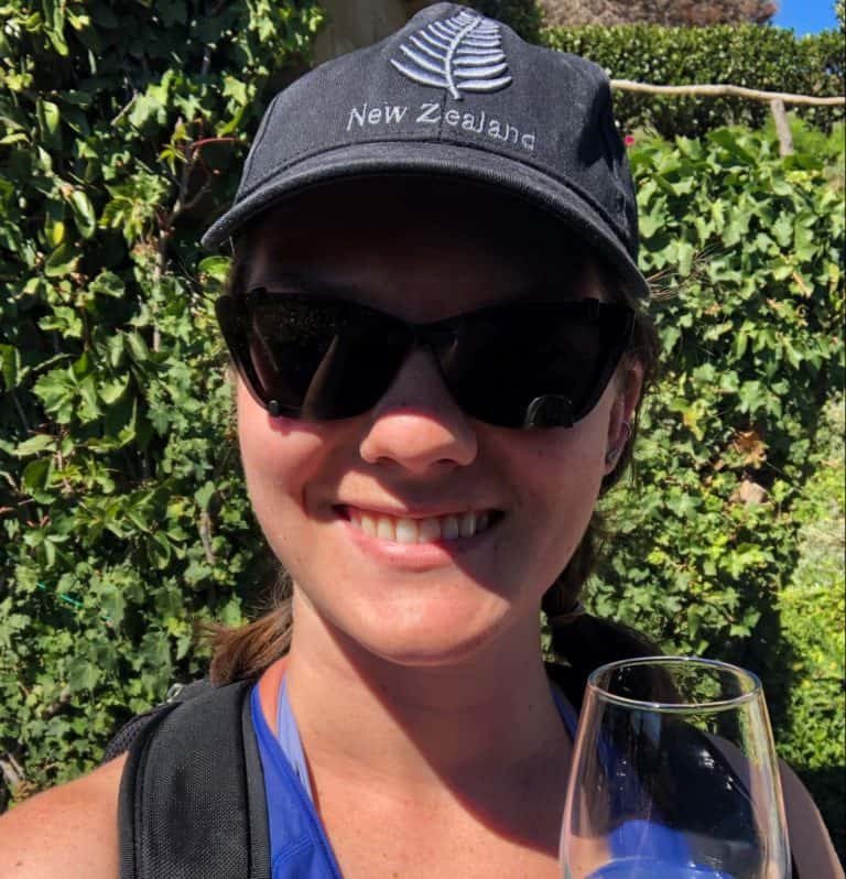 Nina smiling at the camera and holding a glass of white wine on a tour