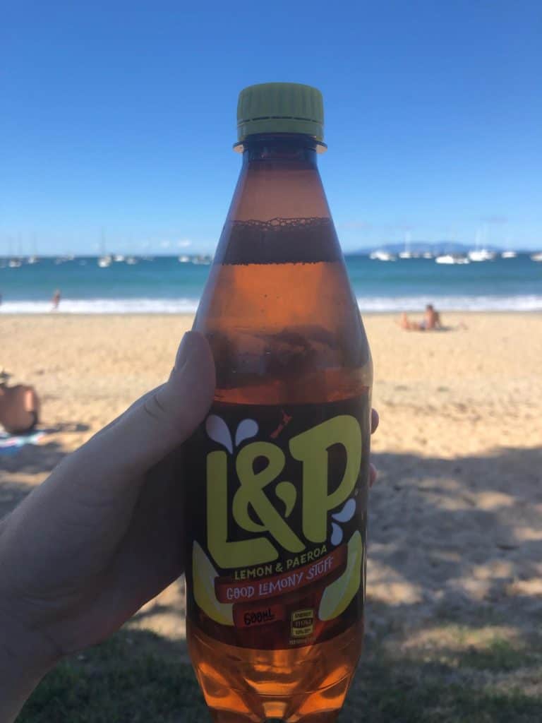 135 New Zealand Slang: From Sweet As to Swear Words 11 L&P soda in Nina's hand on the beach in New Zealand