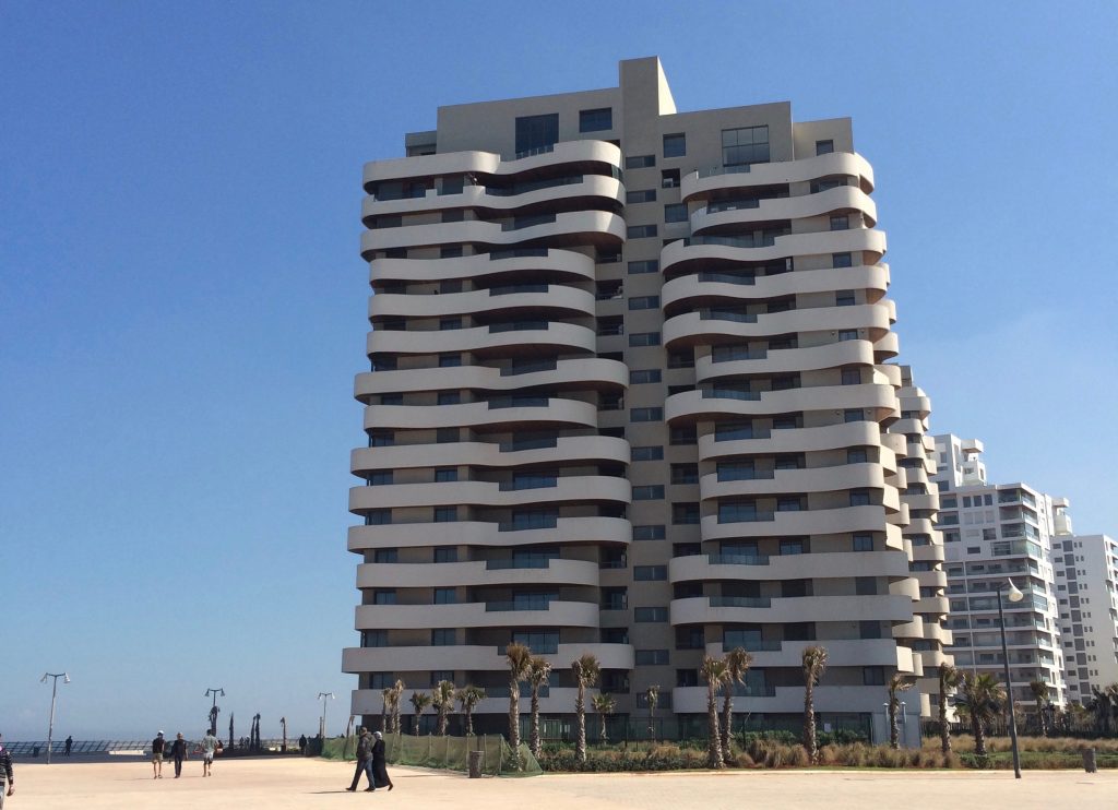 The Unbelievable Location That Made a Travel Pro Say 'Never Again!' 2 Apartment buildings by the ocean in Casablanca with wavy balconies to mimic the waves.