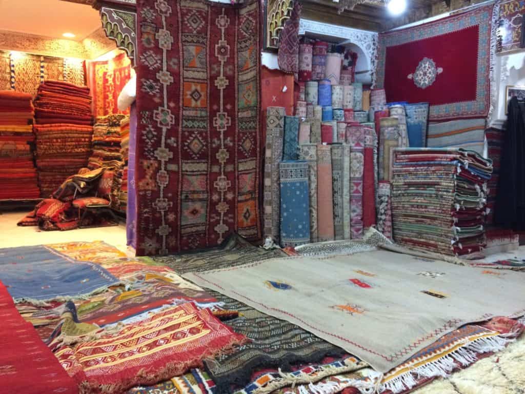 Is Marrakech Safe for Solo Female Travellers? 5 Marrakech rug shop with rugs literally piled to the ceiling, draped over the wall, and collaged across the floor.