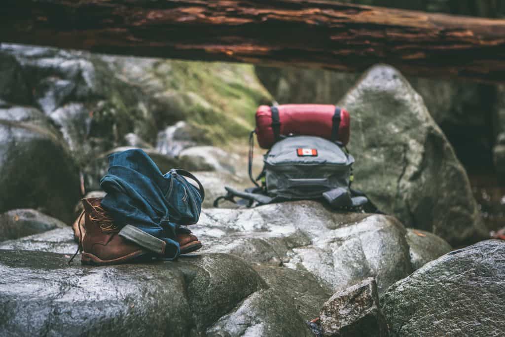 45 Pros and Cons of Living in Canada from a Canadian 17 Backpacks with Canadian flag decals resting on rocks as people hike