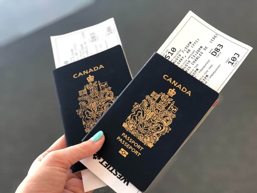 45 Pros and Cons of Living in Canada from a Canadian 14 Image of a woman holding two Canadian passports with flight tickets in them