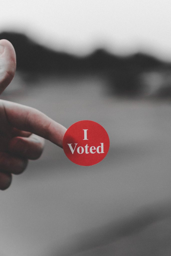 45 Pros and Cons of Living in Canada from a Canadian 8 Person holding an "I voted" sticker