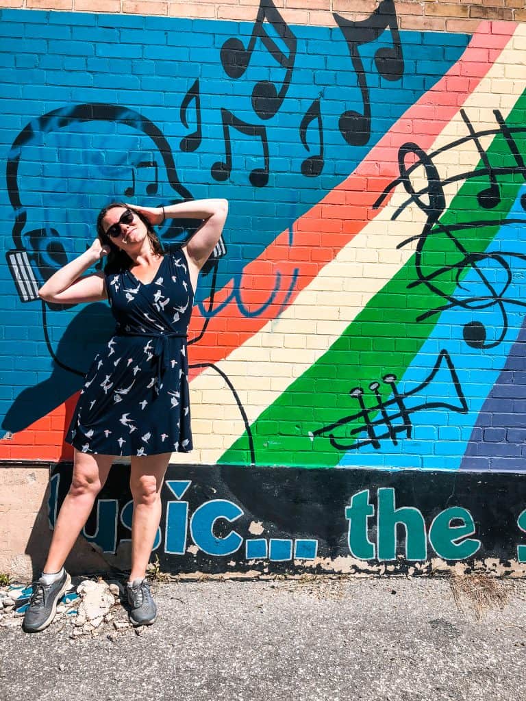 29 Pros and Cons of Living in Toronto (From a Local) 7 Nina in a dress poses against a colorful street mural.