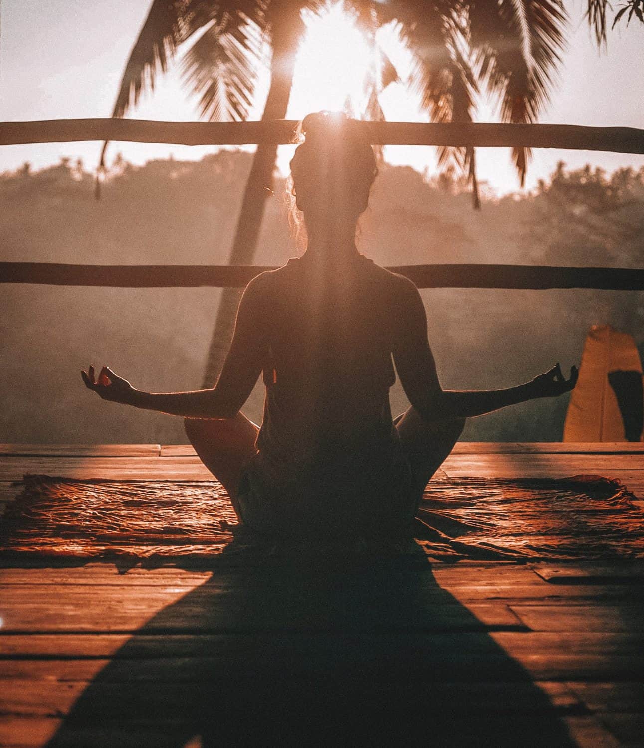 15 Unique Solo Staycation Ideas for Singles 2 Silhouette of a woman meditating in front of palm trees