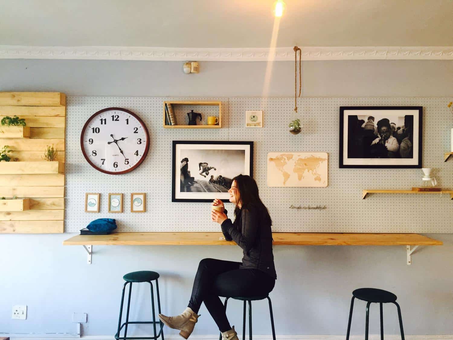 15 Unique Solo Staycation Ideas for Singles 19 Woman laughing at a cafe that is travel themed as she drinks a coffee