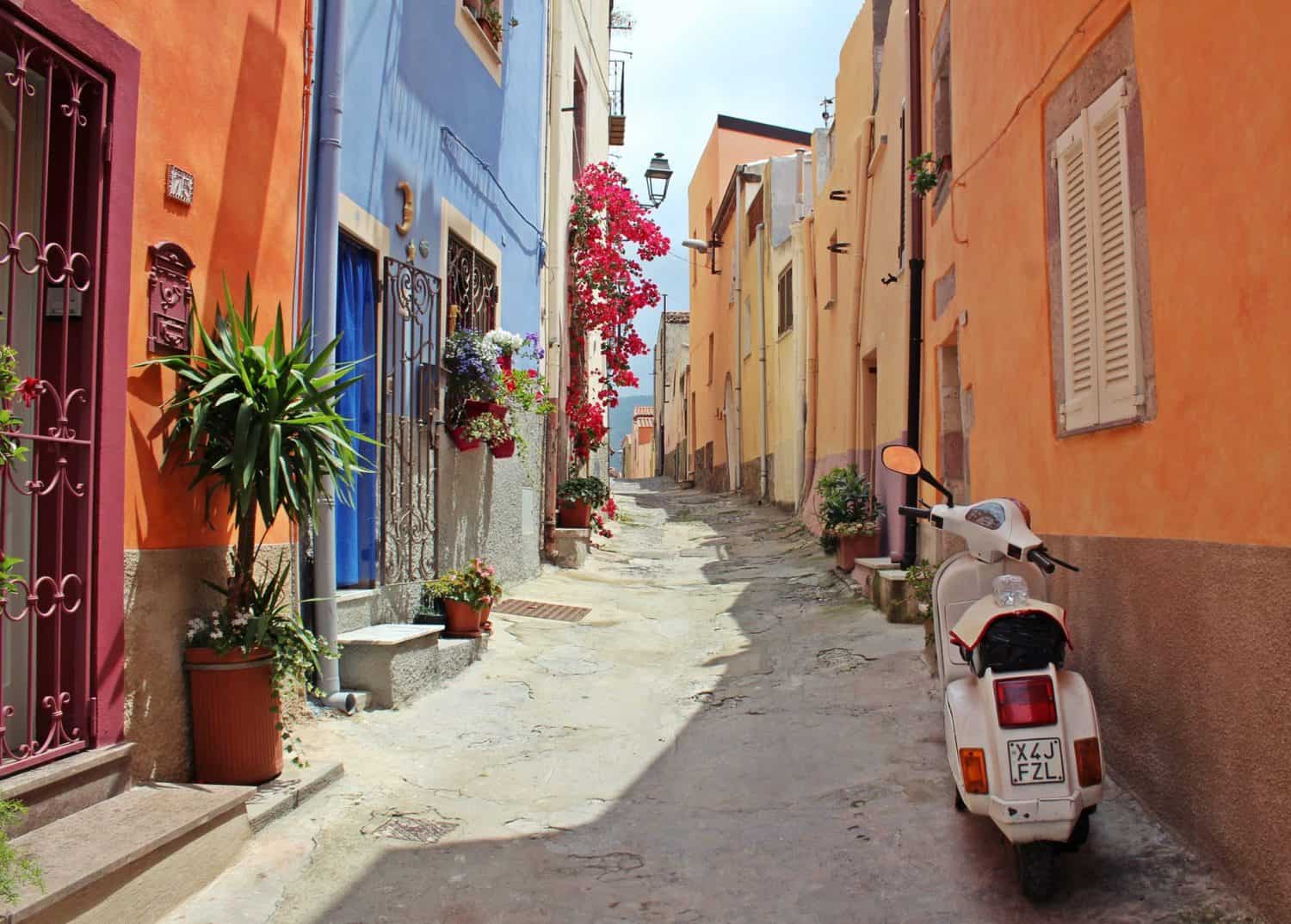 15 Unique Solo Staycation Ideas for Singles 9 Small street of Italy with a white vespa and multi coloured houses