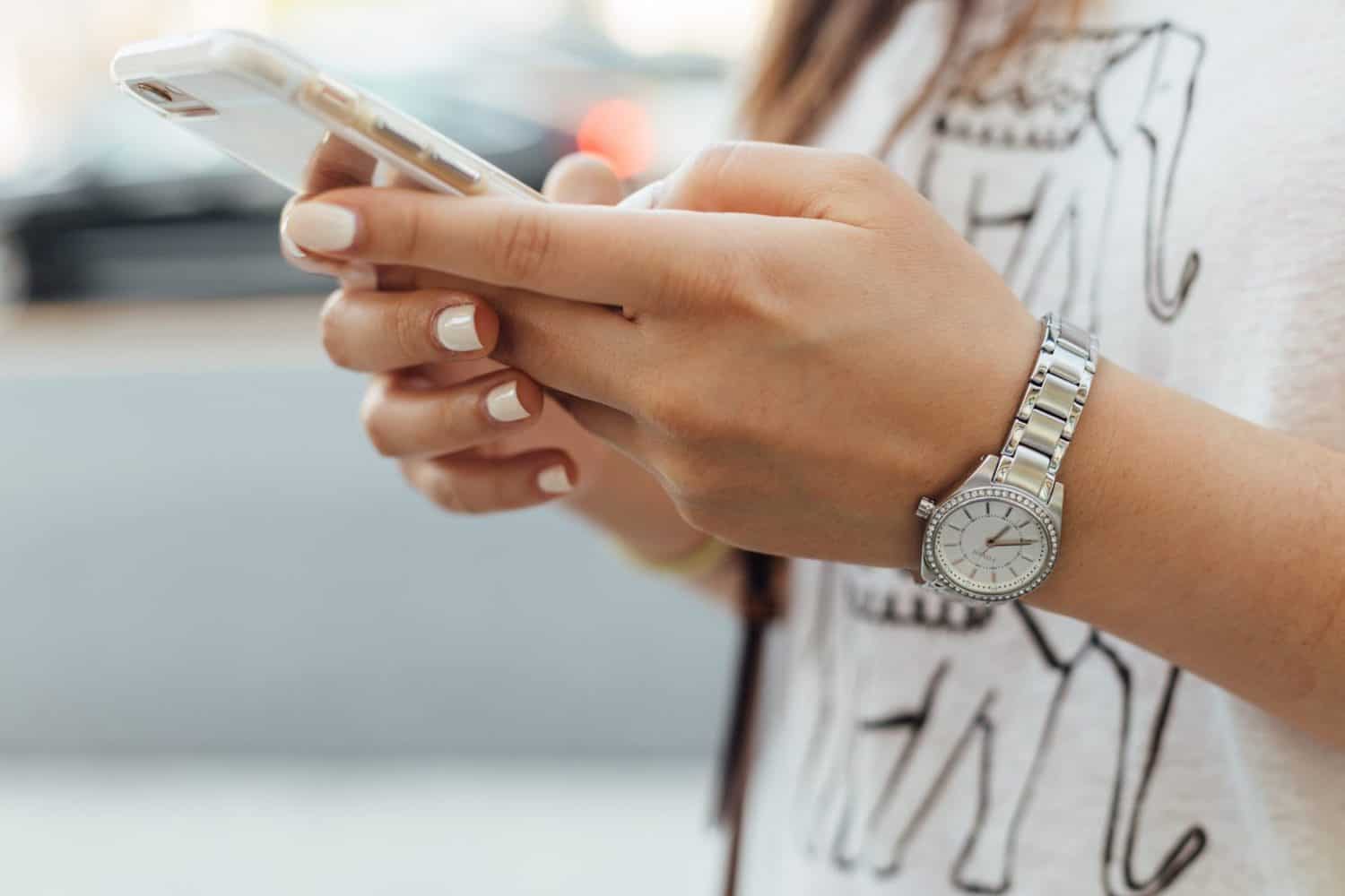 15 Unique Solo Staycation Ideas for Singles 11 Woman with silver watch and white nail polish texting on a phone