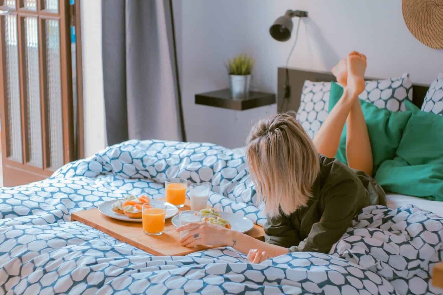 15 Unique Solo Staycation Ideas for Singles 1 Woman treating herself to breakfast in bed on her solo staycation