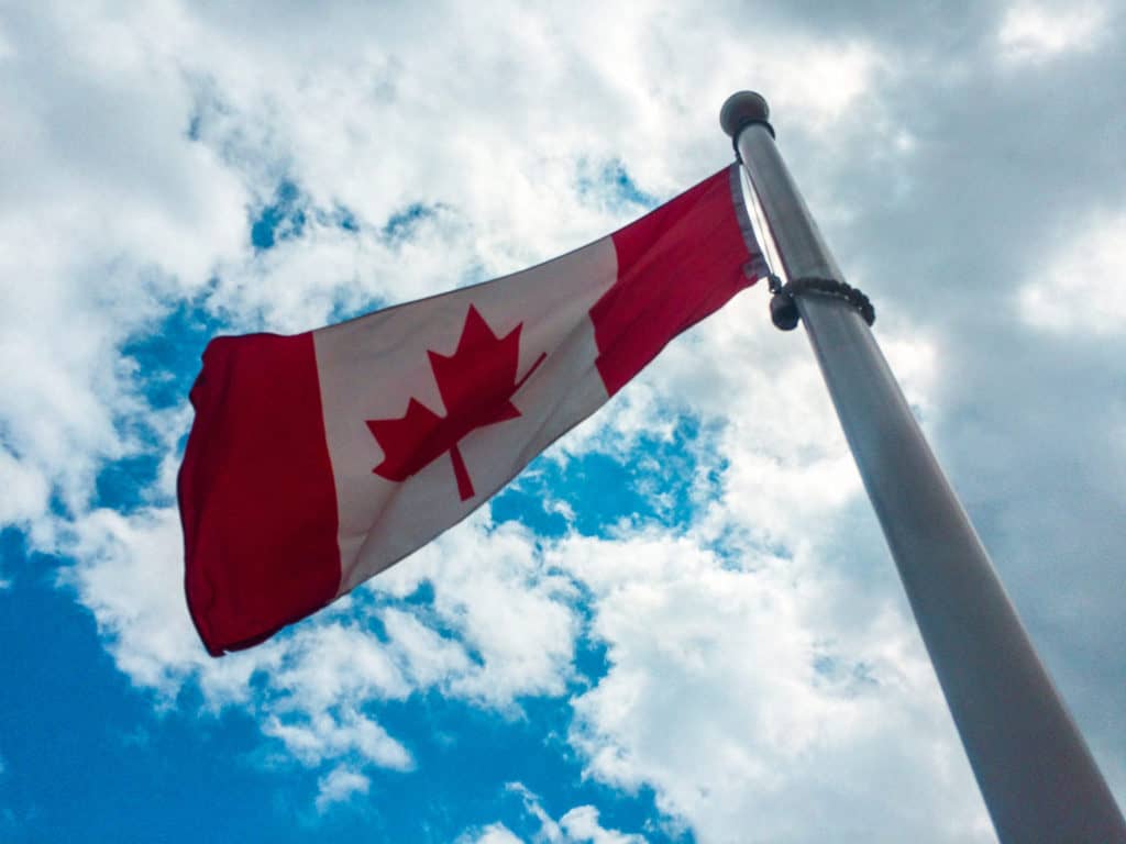 202 Fun Facts About Canada You've Never Heard 1 Canadian flag against a blue cloudy sky