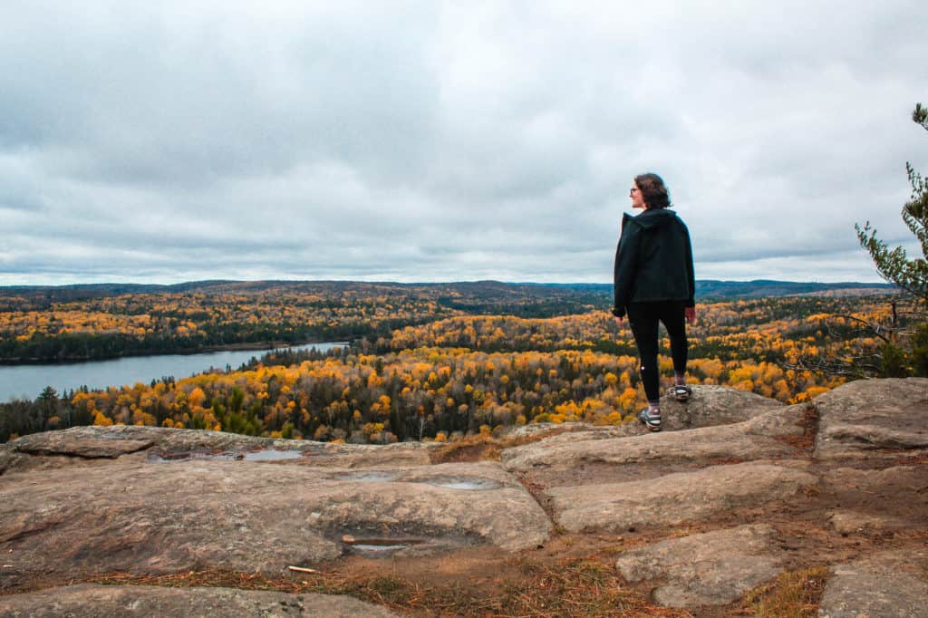 29 Greatest Ways to Make Money Travelling the World 3 Nina standing on a cliff overlooking the golden changing leaves on Algonquin park to show you you can make money from selling travel photos