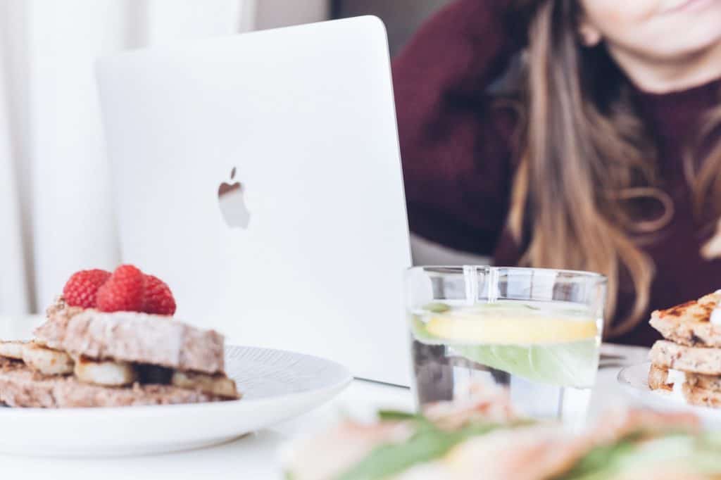29 Greatest Ways to Make Money Travelling the World 7 how to make money freelancing while travelling - Woman working at a Macbook at a cafe with food in a burgundy sweater