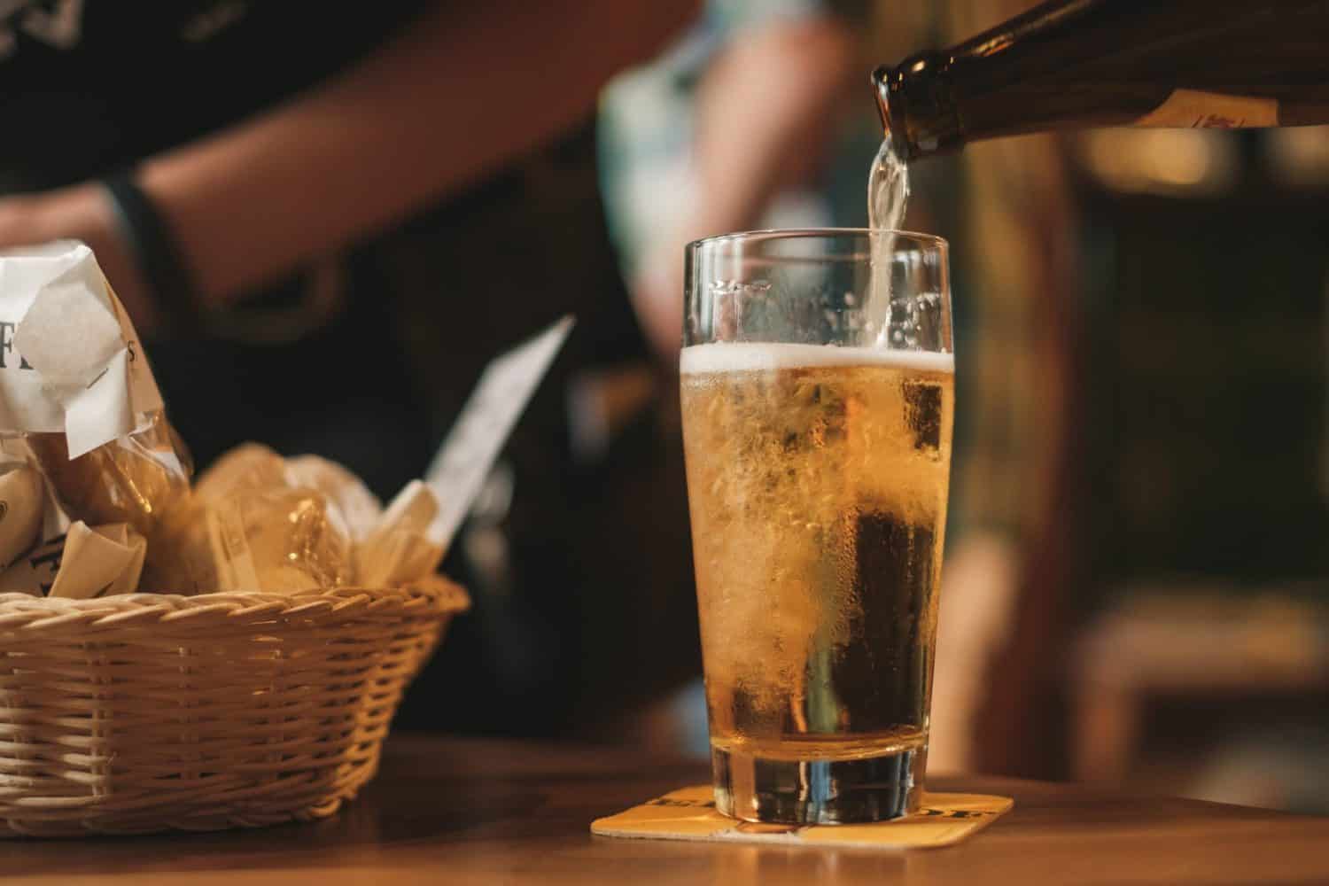 20 Common Misconceptions About Canada: Myths & Stereotypes 3 Pouring a beer into a tall glass beside a basket of bread on a bar counter
