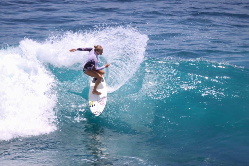 29 Greatest Ways to Make Money Travelling the World 5 Woman surfing on a light blue wave