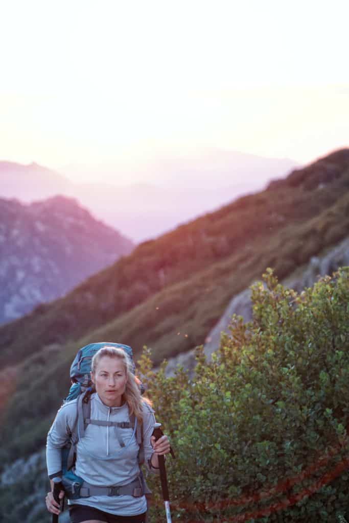 What to Wear Hiking: A Complete Guide for Beginners 23 Woman hiking with trekking poles up a mountain