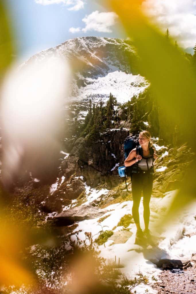 What to Wear Hiking: A Complete Guide for Beginners 4 Woman hiking viewed through blurry leaves