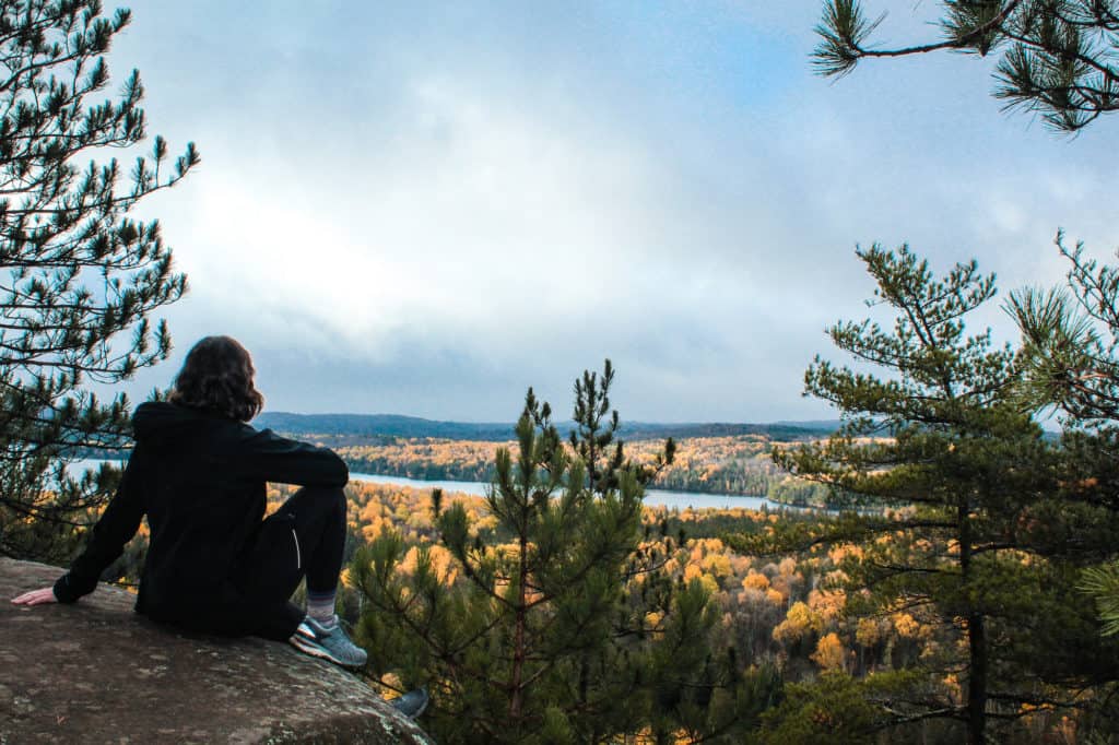 What to Wear Hiking: A Complete Guide for Beginners 27 Nina sitting on a cliffside in Algonquin Park wearing leggings and sneakers.