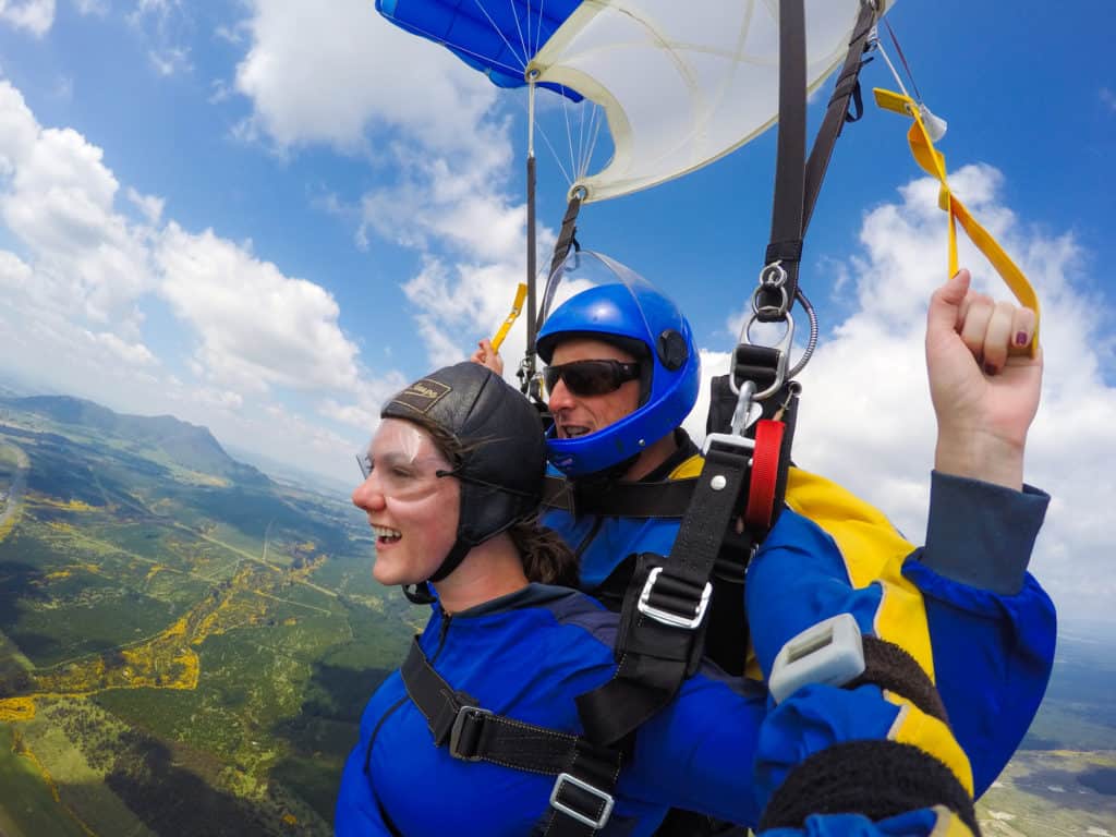 Skydiving in Taupo, New Zealand: 15,000 ft of Fun 11 Nina smiling overlooking the scenery of Taupo as she parachutes from her skydive with her tandem instructor behind her in New Zealand