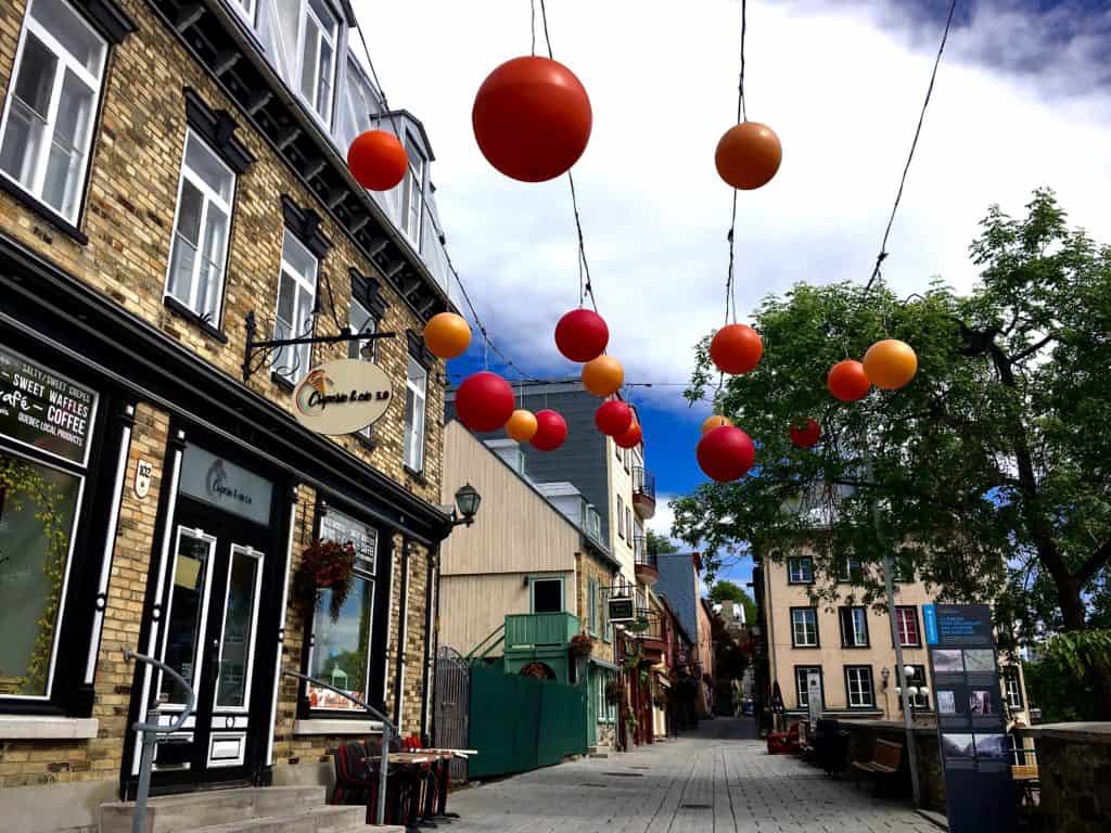 Best Quebec Road Trip (An Epic 2 Week Itinerary) 7 Quebec City street with orange and yellow dangling lights