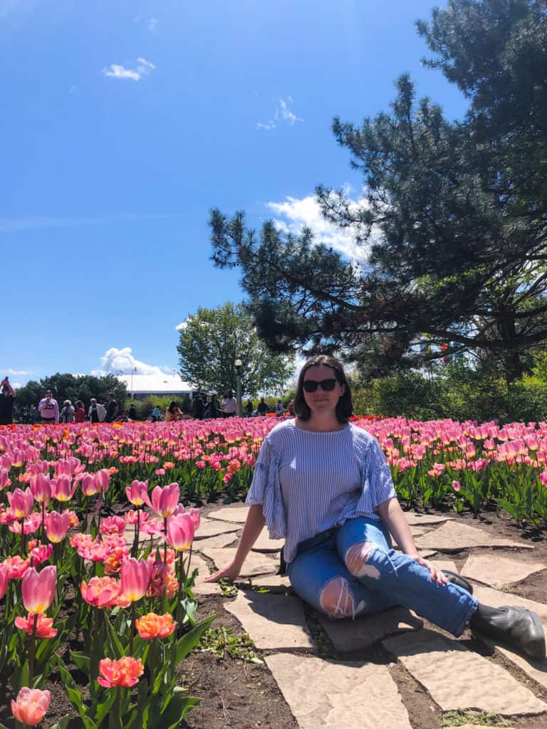 Nina smiling in front of tulips in Ottawa in a solo travel picture
