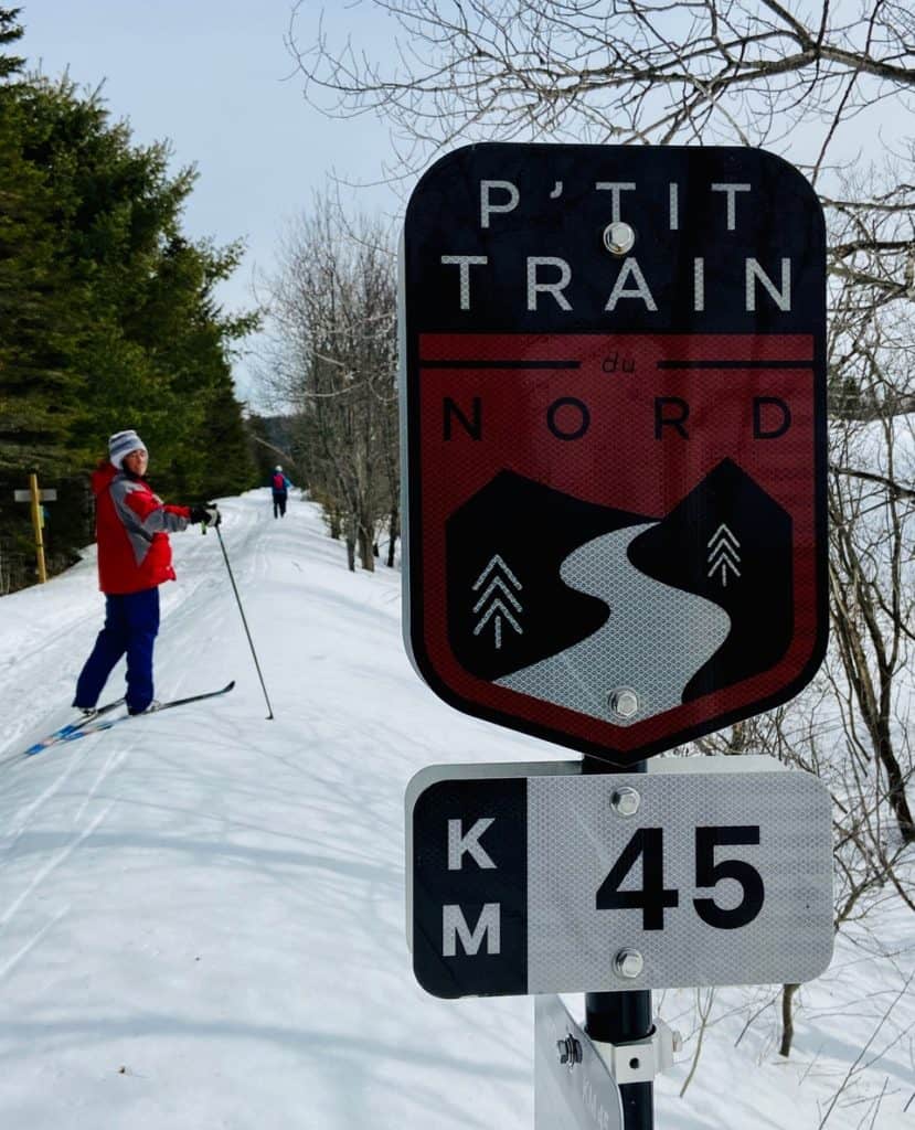 Best Quebec Road Trip (An Epic 2 Week Itinerary) 4 Image of Anne cross country skiing down a trail in Val-David, Quebec