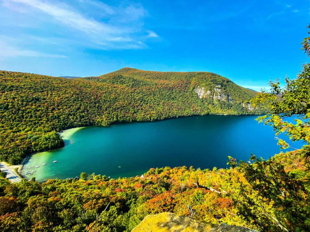 27 Best Weekend Getaways in the US 2 North East Kingdom of Vermont views over the blue lake with green trees in the surrounding forest for the best weekend trip in the USA