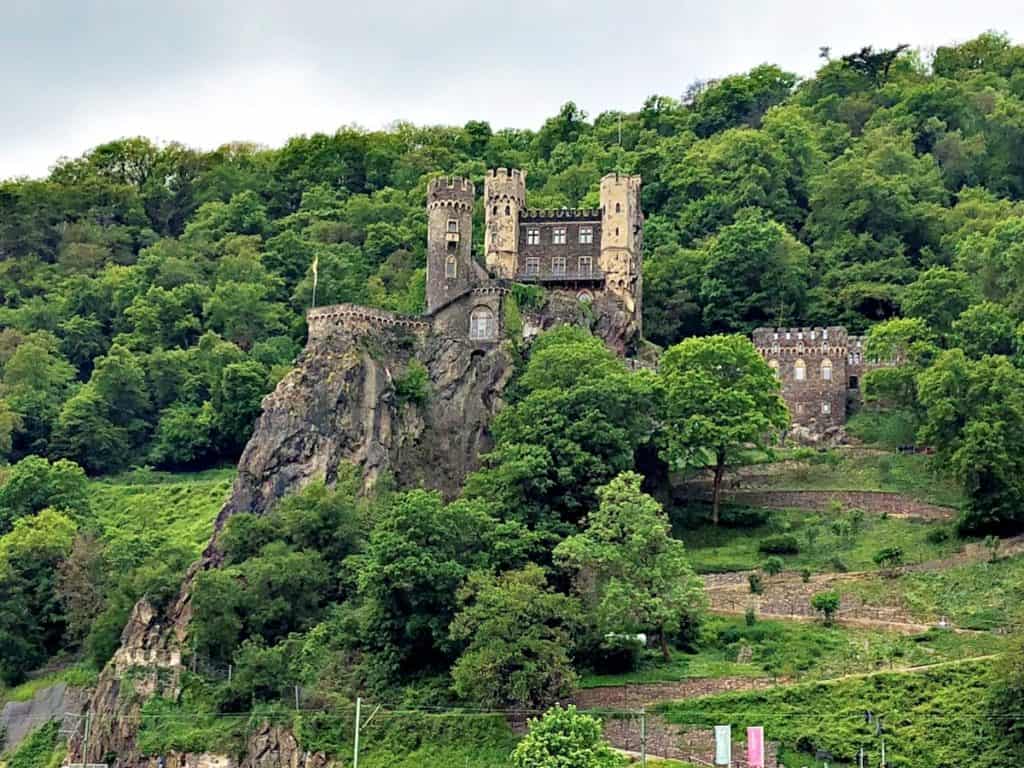 11 Fairytale Castles in Germany: Most Beautiful Castles to Tour 7 Bright green foliage around Burg Rheinstein, sitting in the German hills