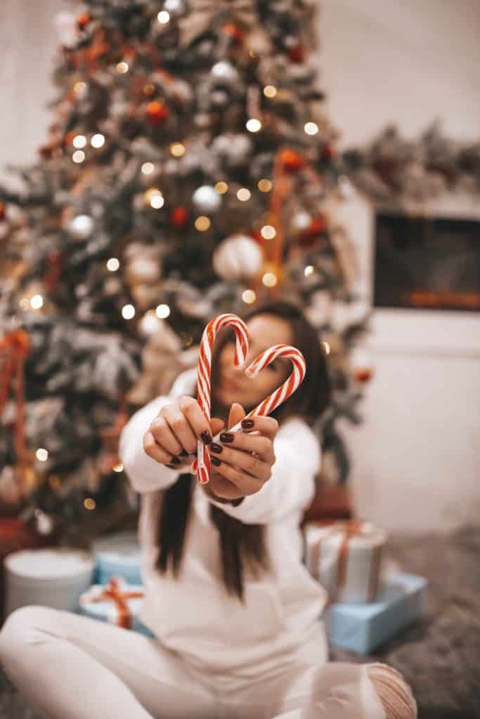 It’s Ok to Spend Christmas Alone (From Someone Who Has!) 5 Woman being alone on christmas holding up two candy canes in the shape of a heart