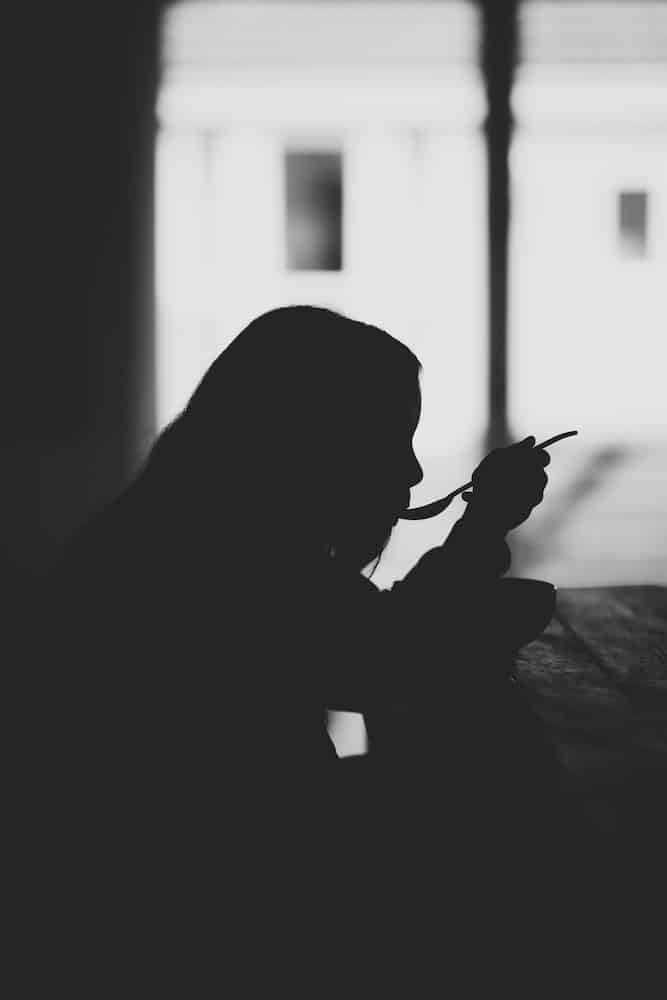 Eating Alone While Traveling: Overcoming Fear of Eating Alone 1 Silhouette of woman eating alone at a table