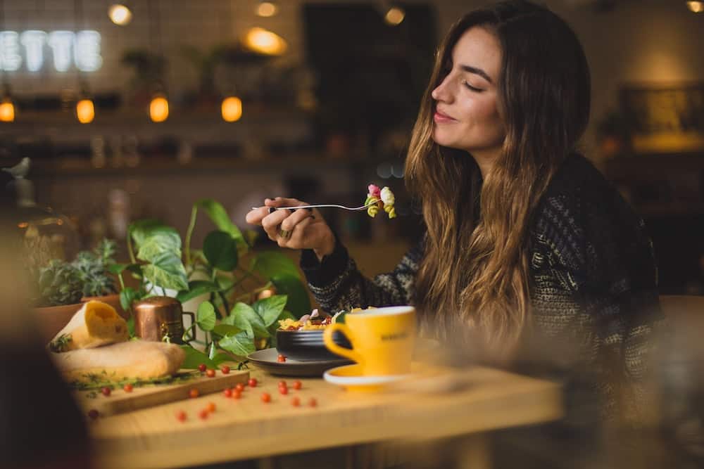 Eating Alone While Traveling: Overcoming Fear of Eating Alone 6 Woman smiling while eating pasta alone in a restaurant
