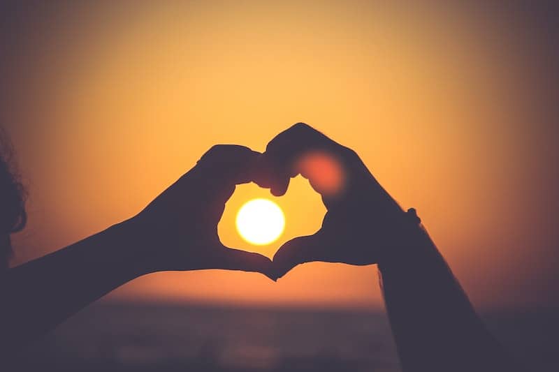 How to Say I Love You in 100 Different Languages 4 Hands shaping a heart over a setting sun