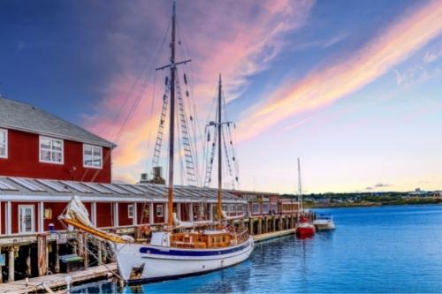 3 Best Halifax Hotels with Waterslides Locals Love 6 Sunset streaking the sky behind a wooden ship in the Halifax harbour