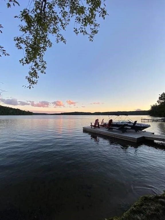 20 Top Airbnb Cottages in Muskoka for an Epic Getaway 30 3-mile lake dock with Muskoka chairs and a motorboat at sunrise