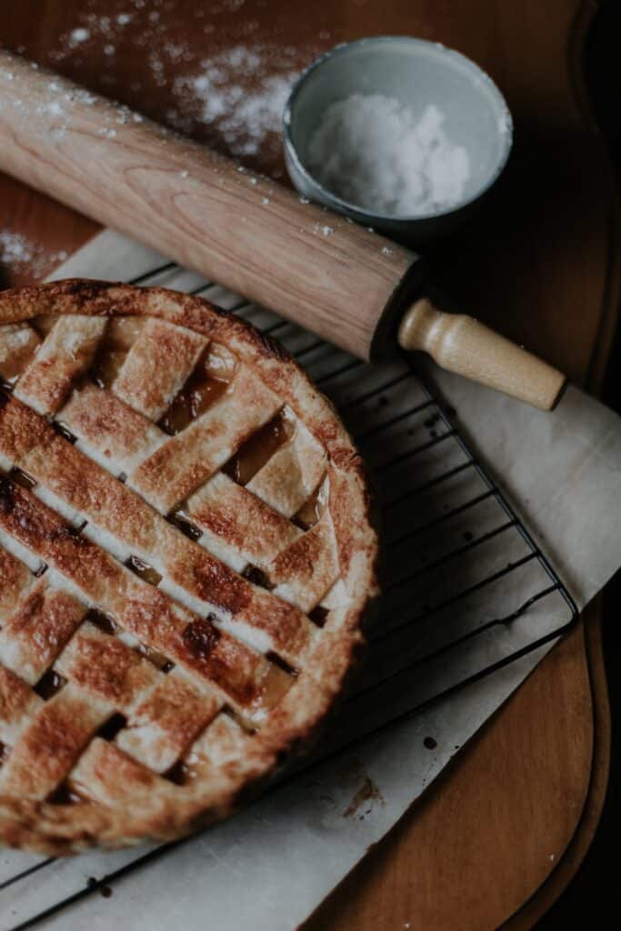 Canada in Autumn: 15 Reasons to Visit + Weather Guide 9 A freshly baked apple pie cooling on a wire rack next to a flour-dusted rolling pin and a cup of flour.