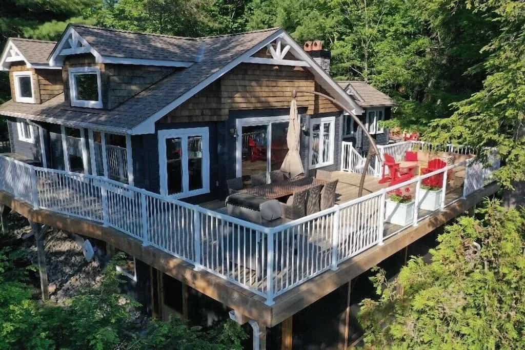 20 Top Airbnb Cottages in Muskoka for an Epic Getaway 53 Blue grey cottage at the cottage compound with oak shakers and multiple seating areas on the patio.