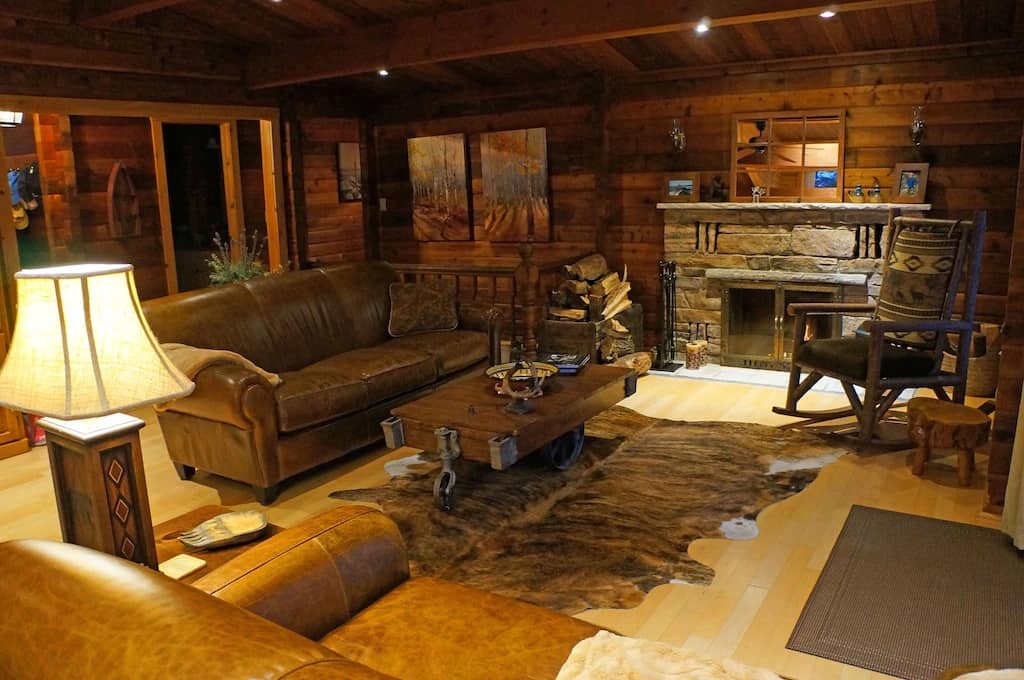 20 Top Airbnb Cottages in Muskoka for an Epic Getaway 54 Living room. Warm wood walls and ceiling with light wood floors. Leather couches and wooden accents. Stone fireplace.