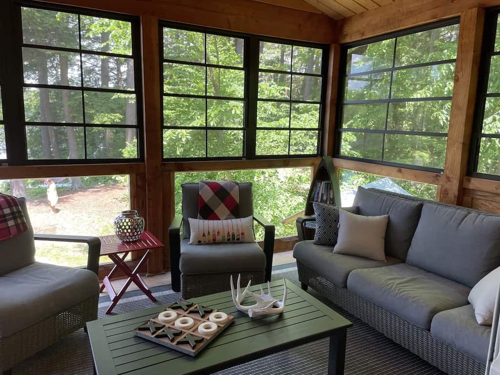 20 Top Airbnb Cottages in Muskoka for an Epic Getaway 13 Muskoka room of Peaceful Crane Lake Cottage. Grey couches around a wood table with an xs and os game.