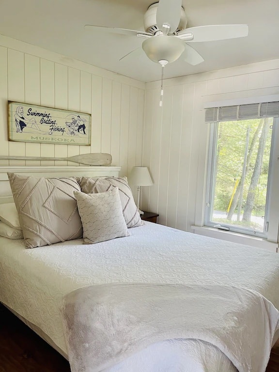 20 Top Airbnb Cottages in Muskoka for an Epic Getaway 47 White panelling bedroom with king sized bed and a white canoe paddle mounted on the wall.