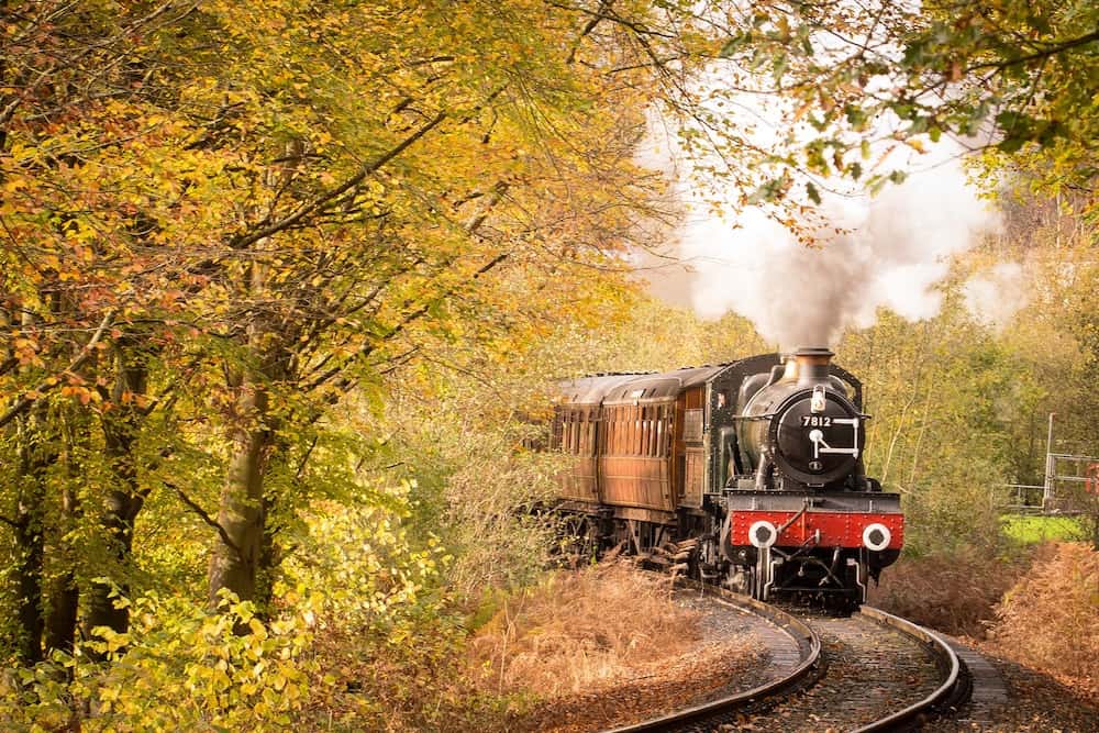 Canada in Autumn: 15 Reasons to Visit + Weather Guide 7 Old fashioned train going through fall leaves in Canada.