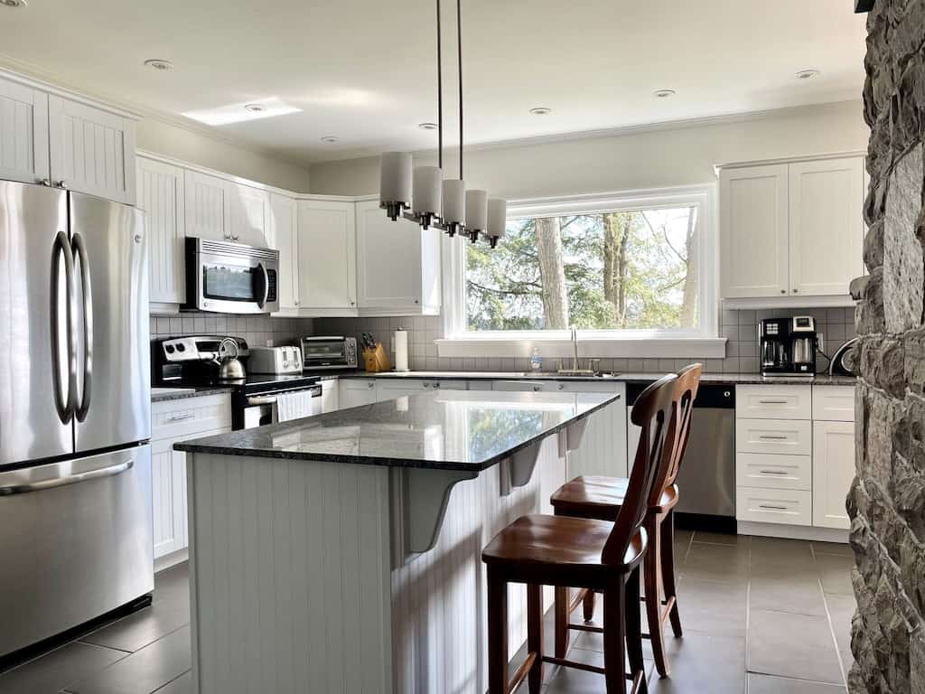 20 Top Airbnb Cottages in Muskoka for an Epic Getaway 38 Family Friendly Lake Joseph kitchen. Large stainless steel appliances with an island and wooden stools.