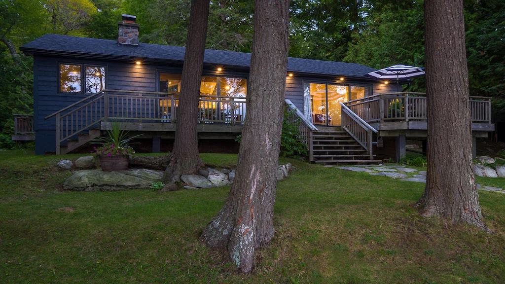 20 Top Airbnb Cottages in Muskoka for an Epic Getaway 45 Black exterior of the New Build Lake Rosseau with golden glow through the windows.